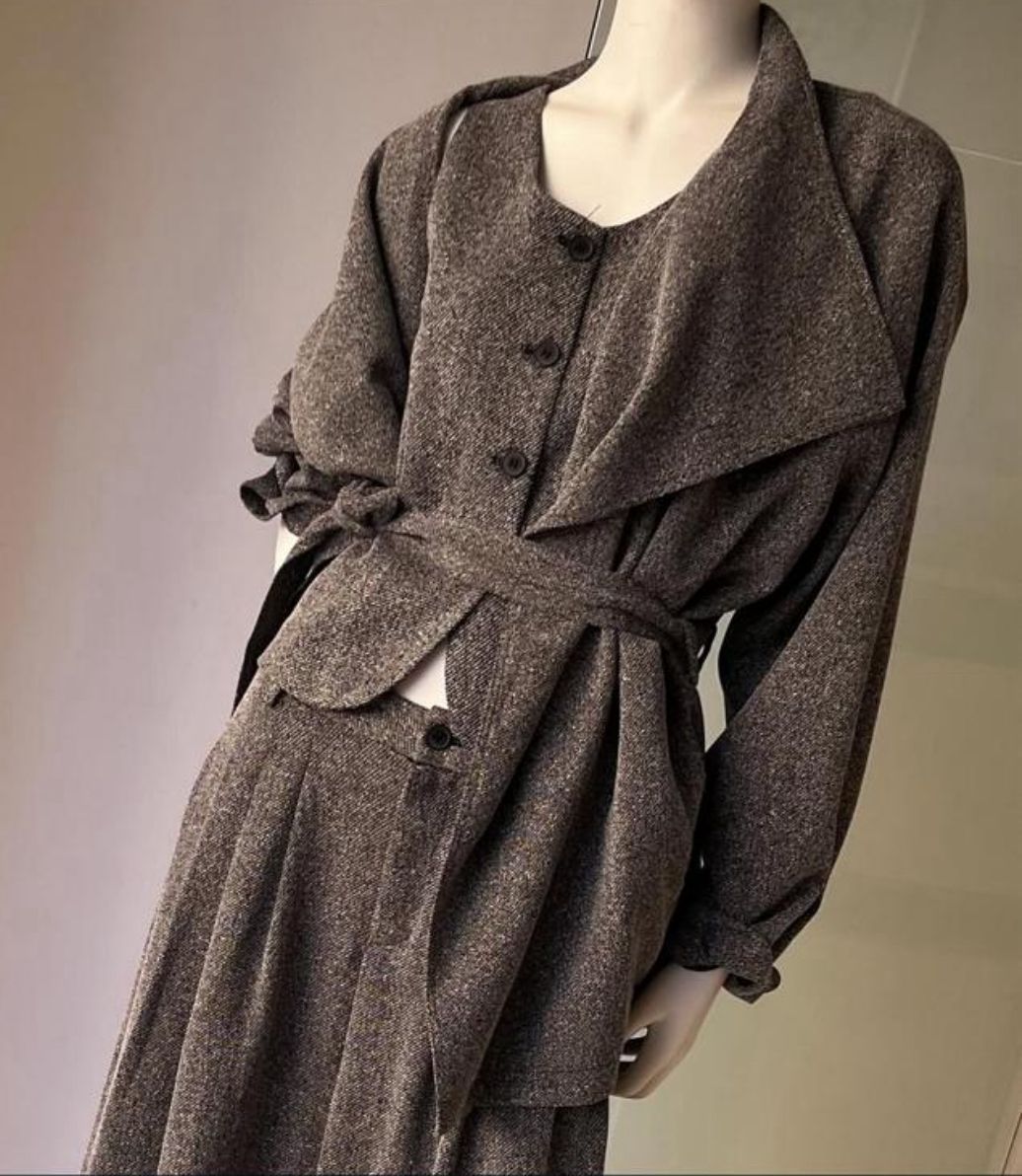 Manichino con trench marrone; appendiabiti sullo sfondo.