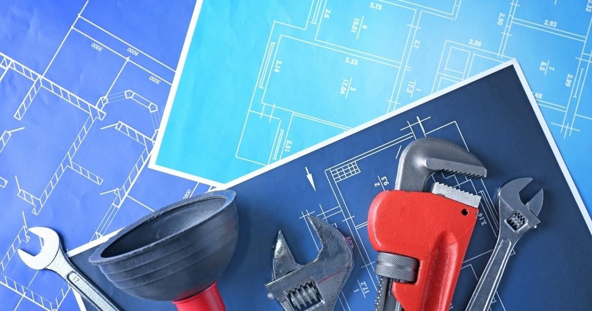 Plumbing tools on top of blue architectural blueprints.