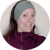 A woman wearing a headband and a purple jacket is smiling in a circle.