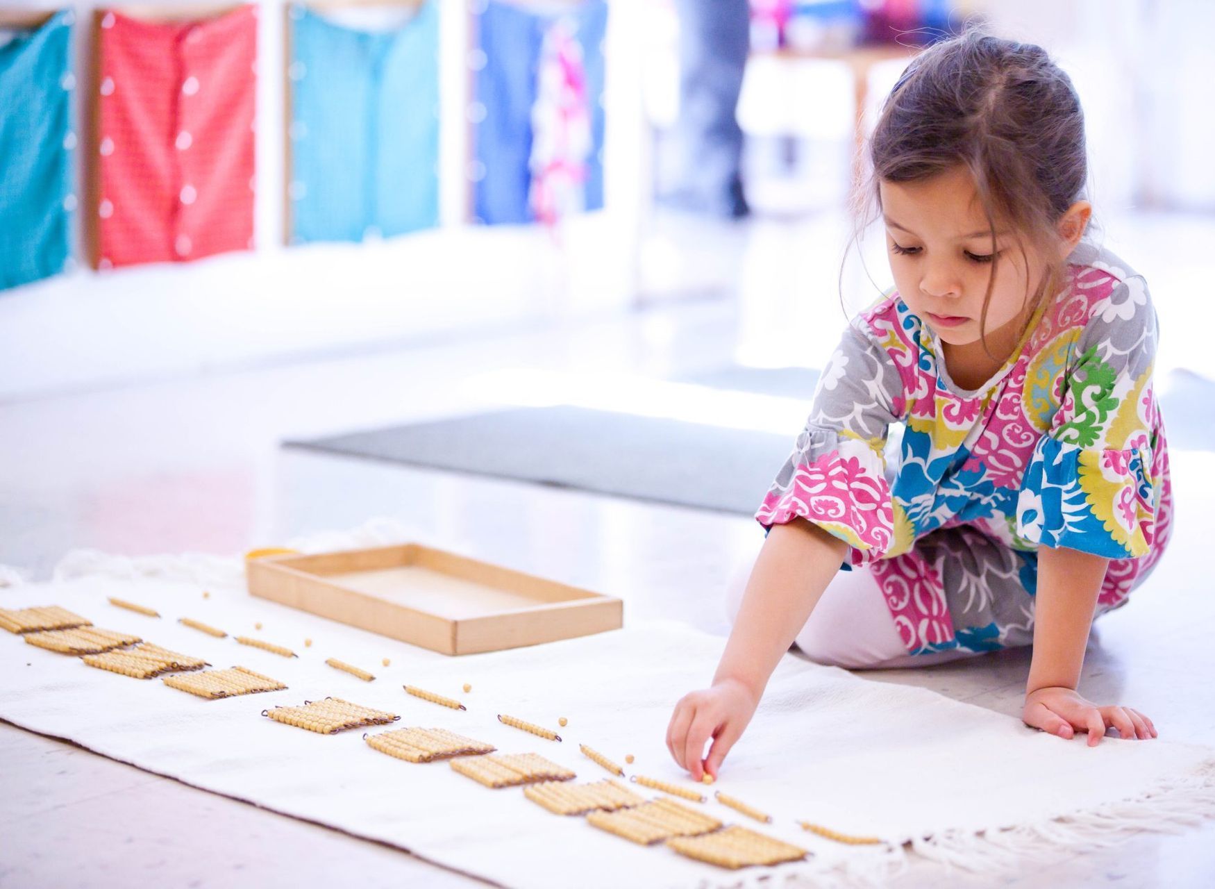 Child working with the Montessori Golden Beads math material
