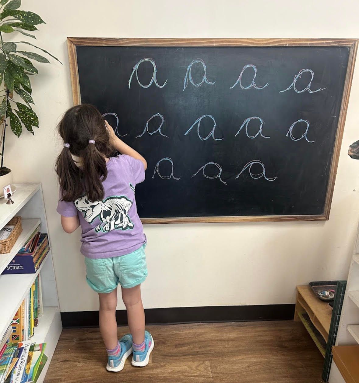 Child writing on chalkboard cursive montessori
