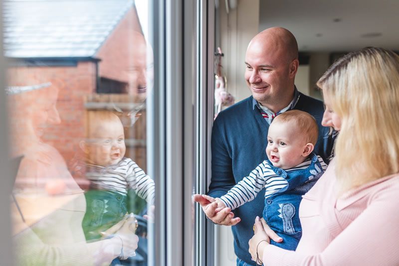 Couple and baby looking through double-glazed windows
