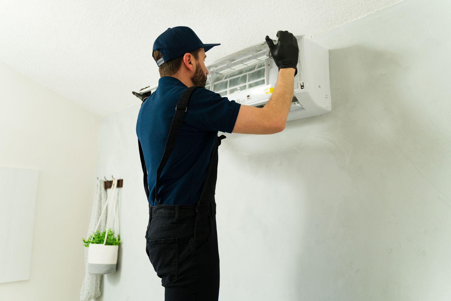 An air conditioning installation contractor mounting a new wall-mounted AC unit indoors.