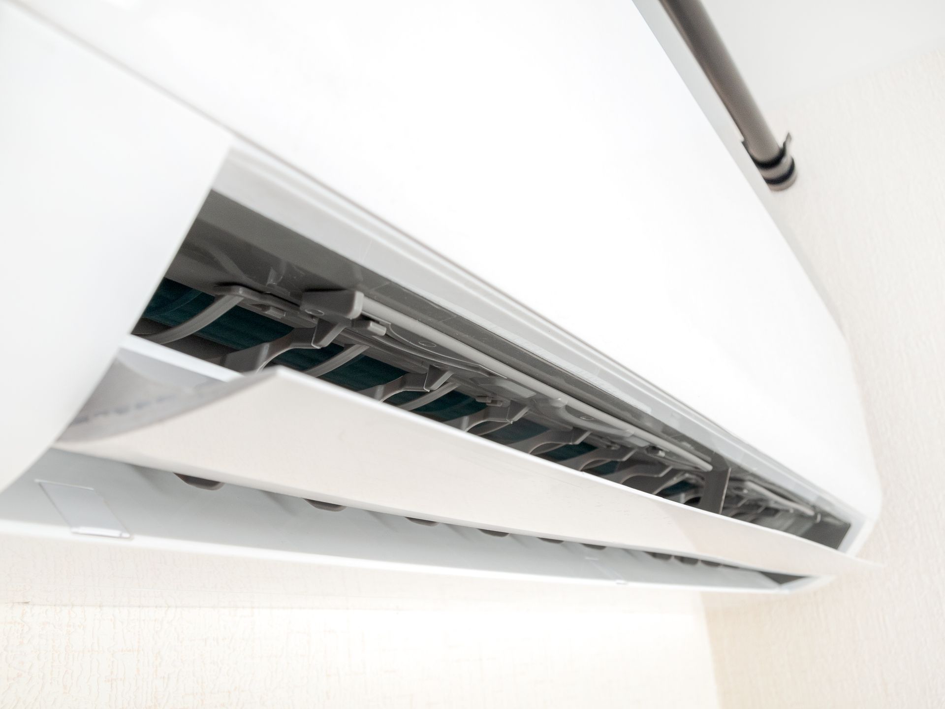 White air conditioner mounted on a wall, vents open, angled shot.