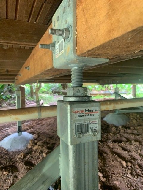 Adjustable steel post jack supporting a wooden deck beam under a raised structure