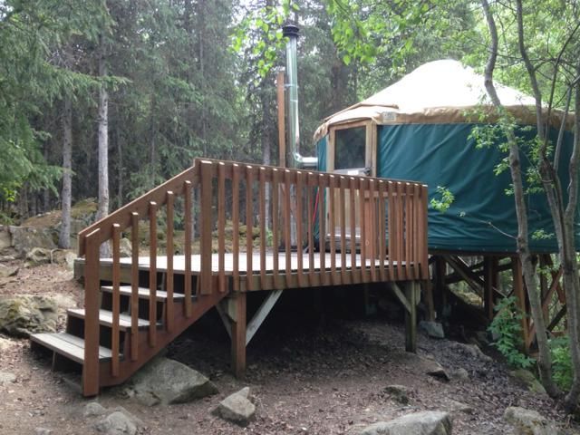 A yurt with a deck and stairs in the woods