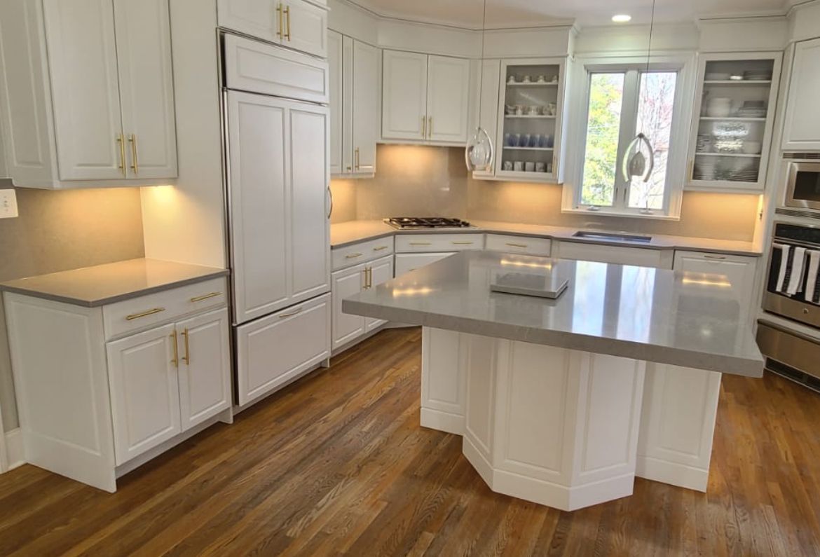 White kitchen with island, cabinets, countertops, and wood flooring.