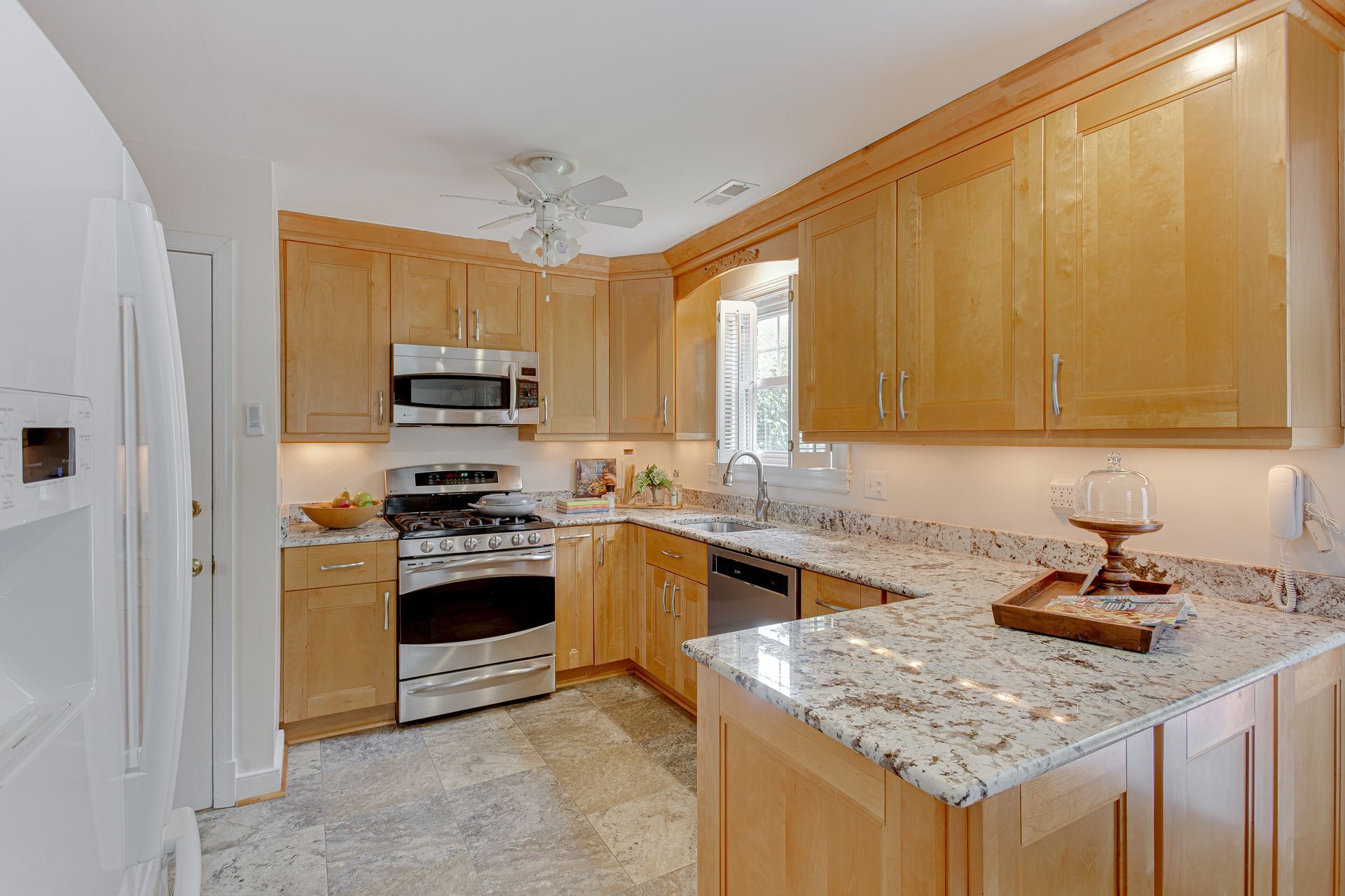 A U-shaped kitchen with light wood cabinets, stainless steel appliances, and granite countertops.