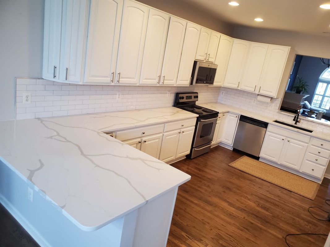 White kitchen with marble countertops, white cabinets, and stainless steel appliances.
