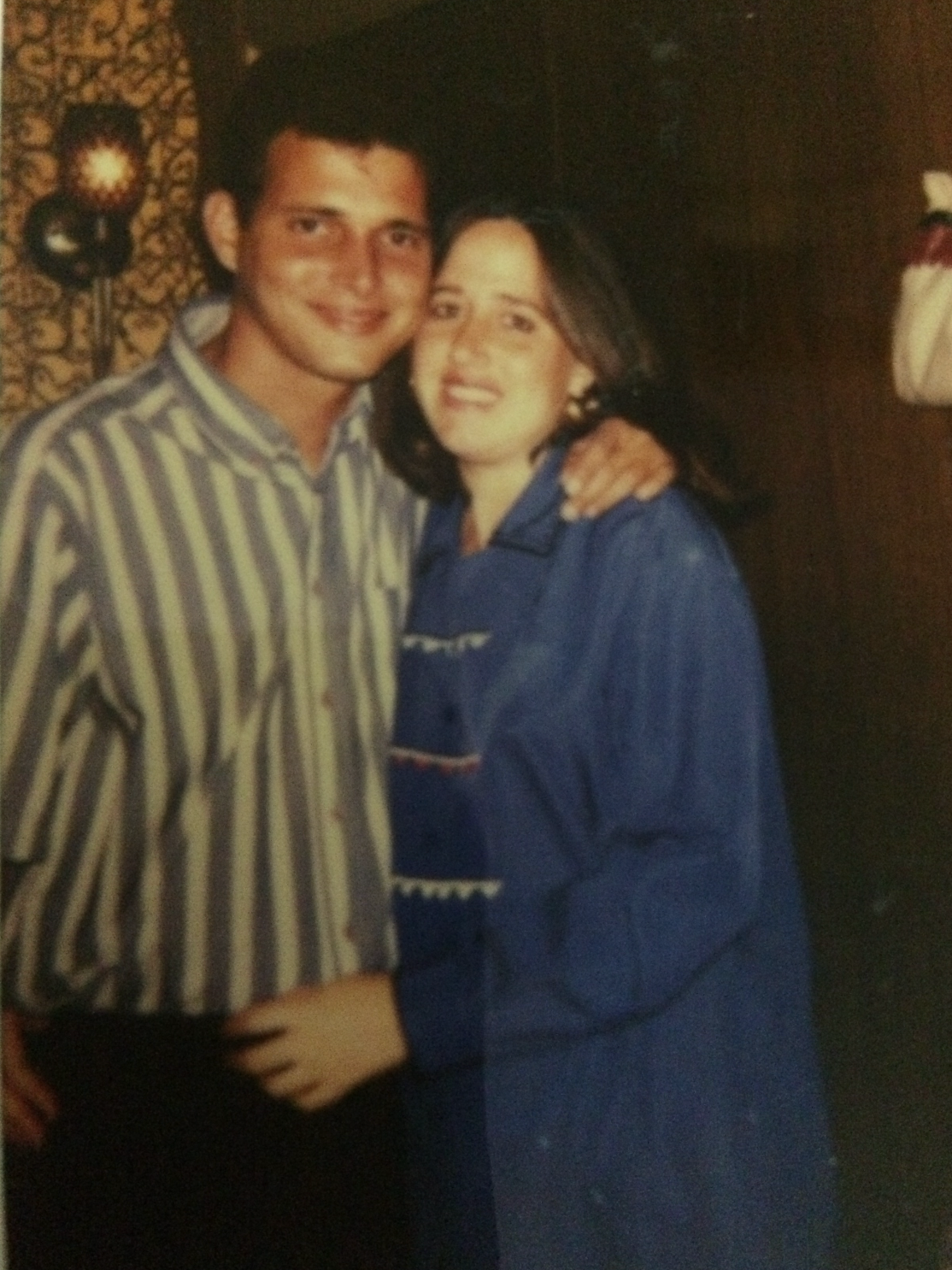 A man in a striped shirt is hugging a woman in a blue jacket