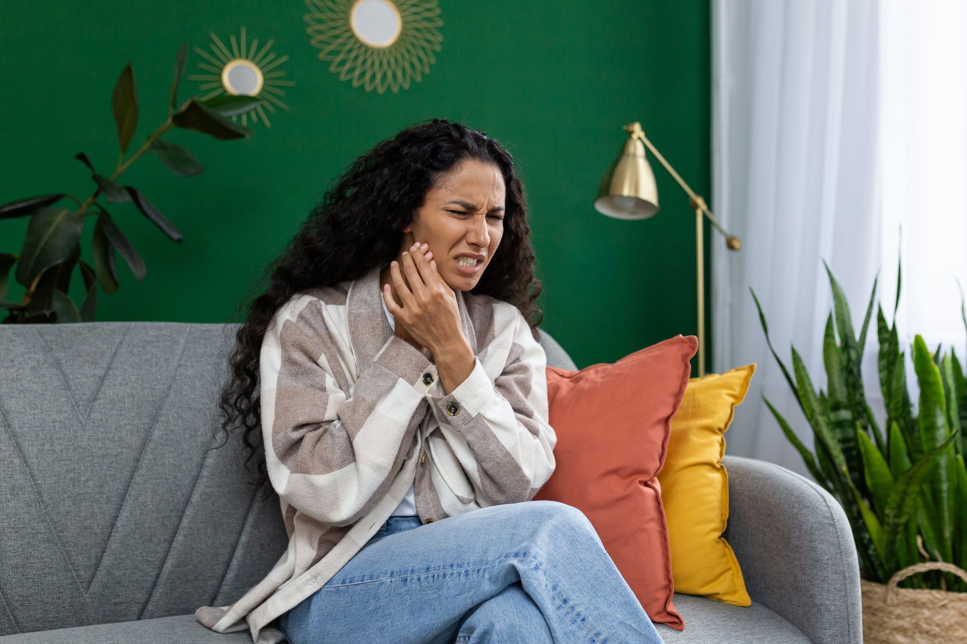 A woman is sitting on a couch with a toothache.