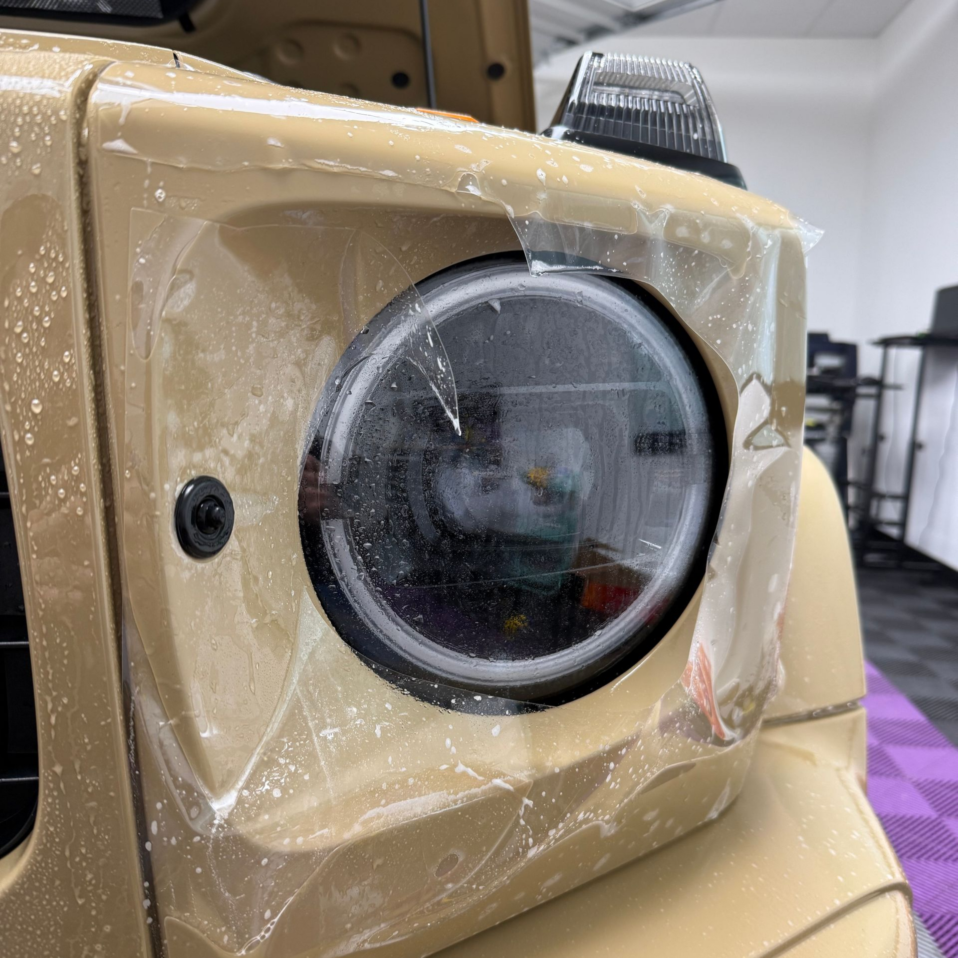 Tan SUV headlight with protective film applied.