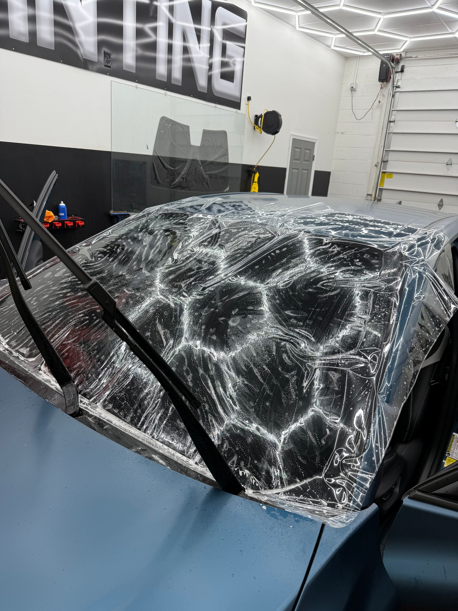 Car windshield covered with water and film, in a professional shop, ready for tinting.
