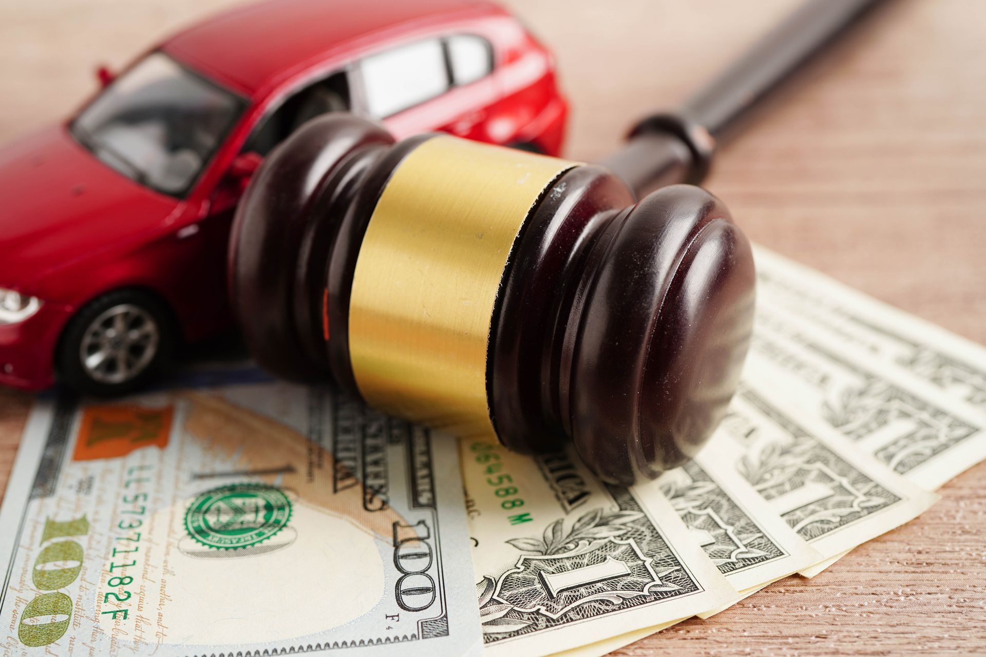 Judge’s gavel with money and car model for car accident lawsuit idea.