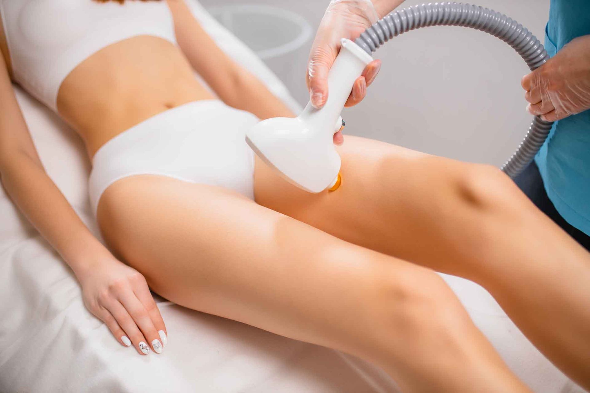 A woman is getting a laser hair removal treatment on her legs.