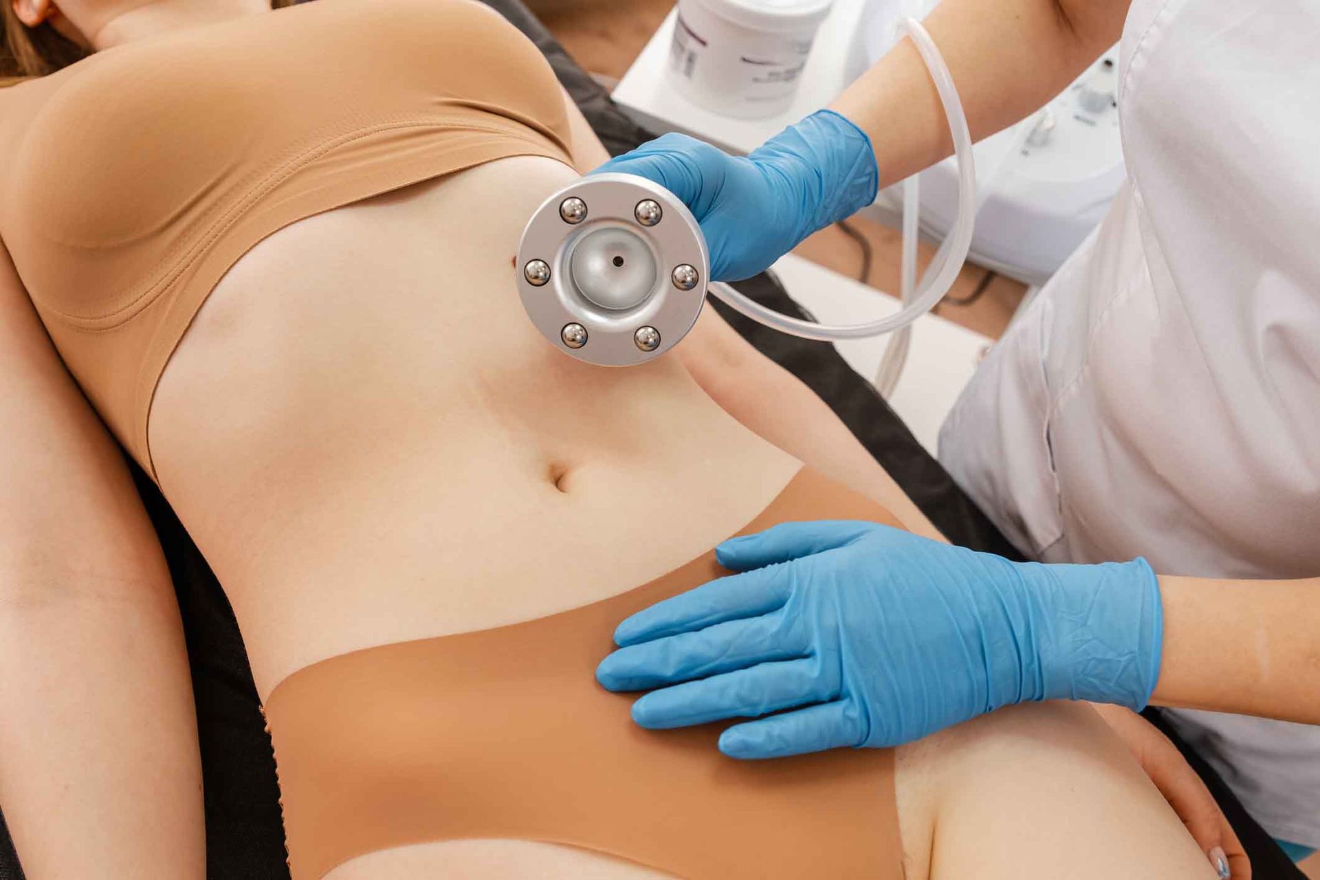 A woman is getting a cavitation treatment on her stomach.
