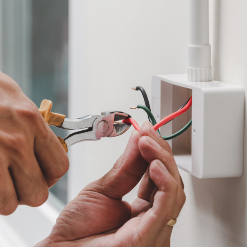 A person is cutting wires with a pair of pliers