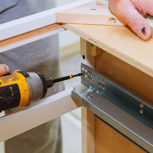 A person is using a screwdriver to fix a piece of furniture