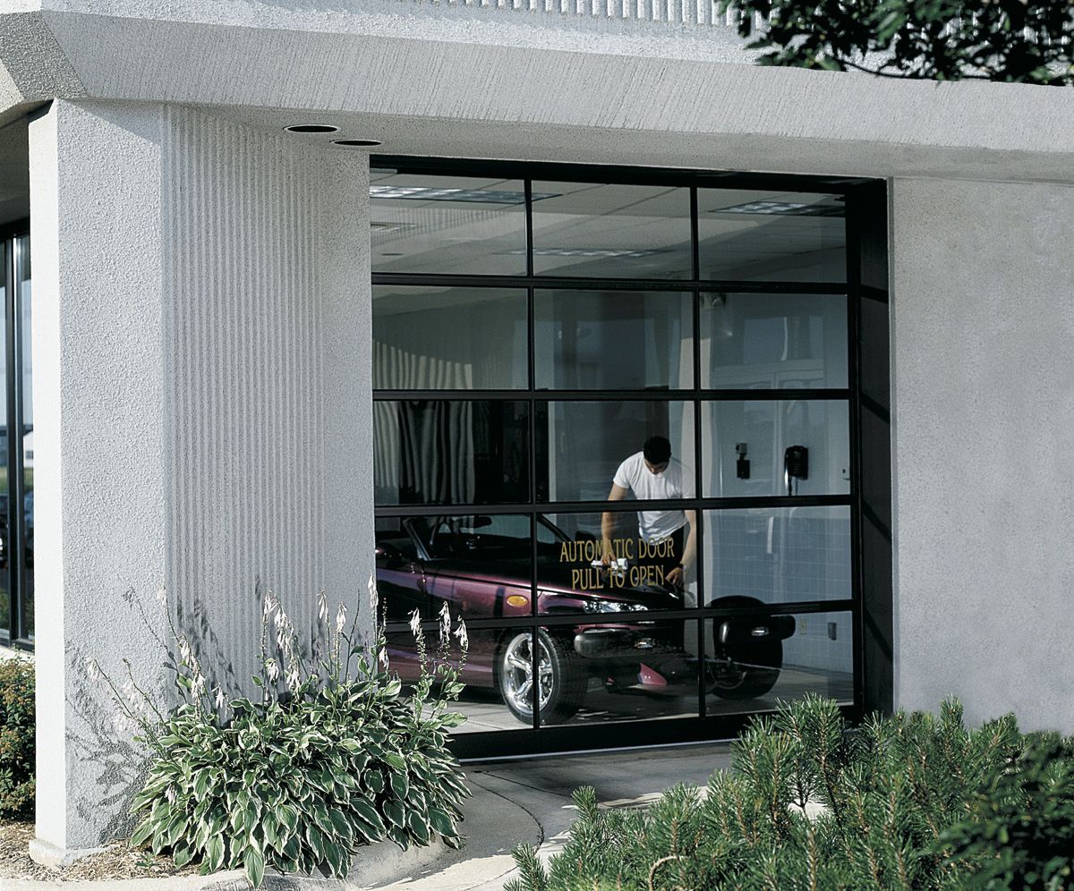 A man is standing in front of a garage with a car in it