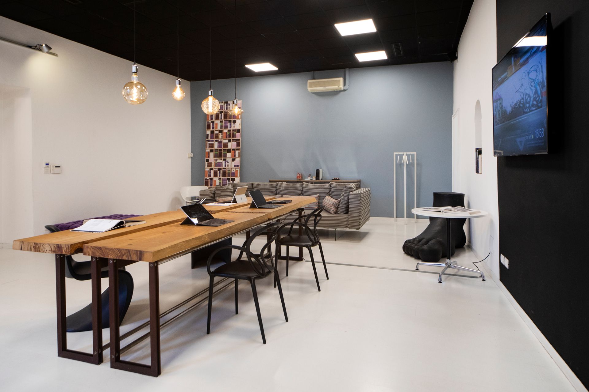 Modern office space with a long wooden table, chairs, and a sofa.