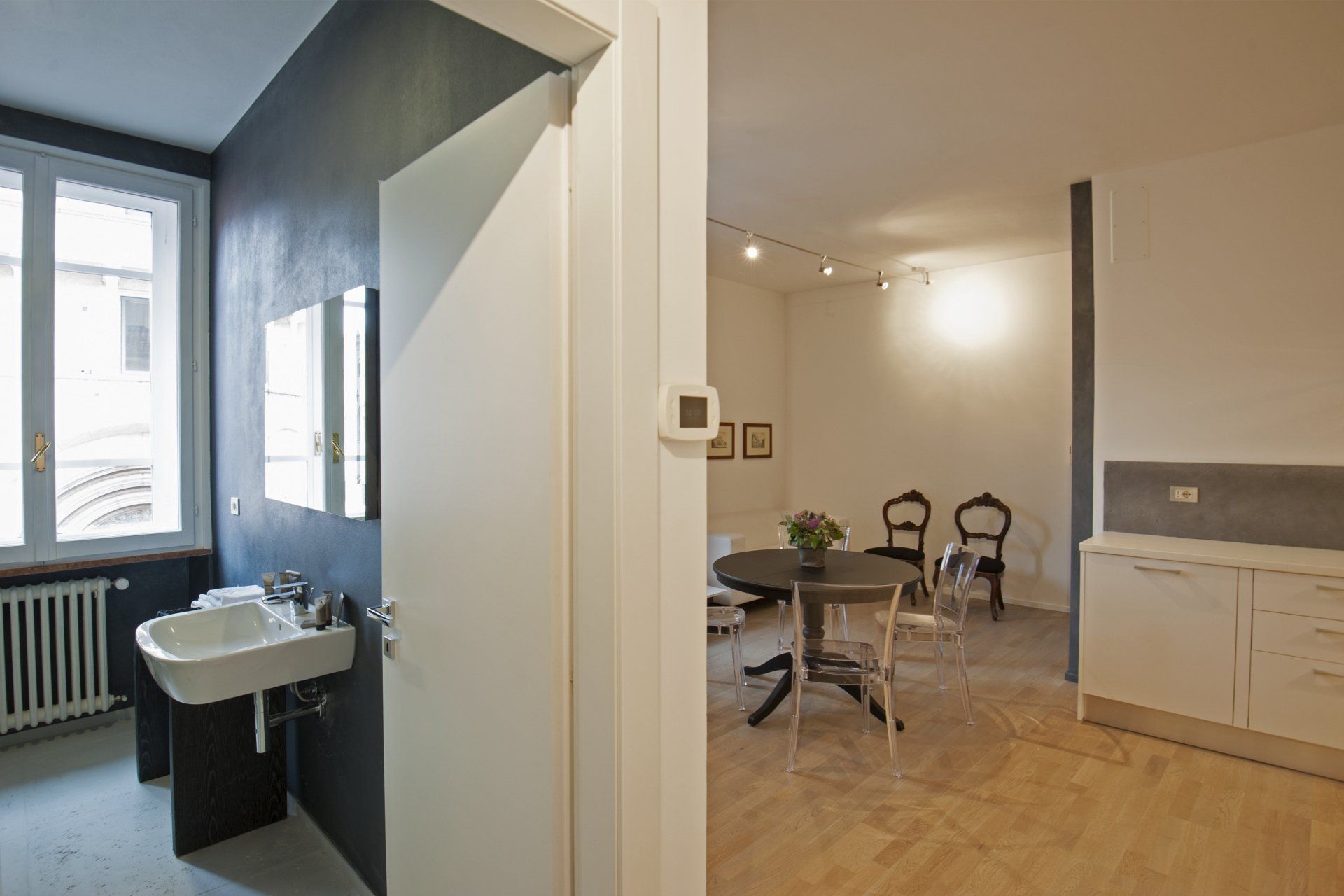 Un bagno con lavandino e porta aperta su una zona pranzo con tavolo e sedie.