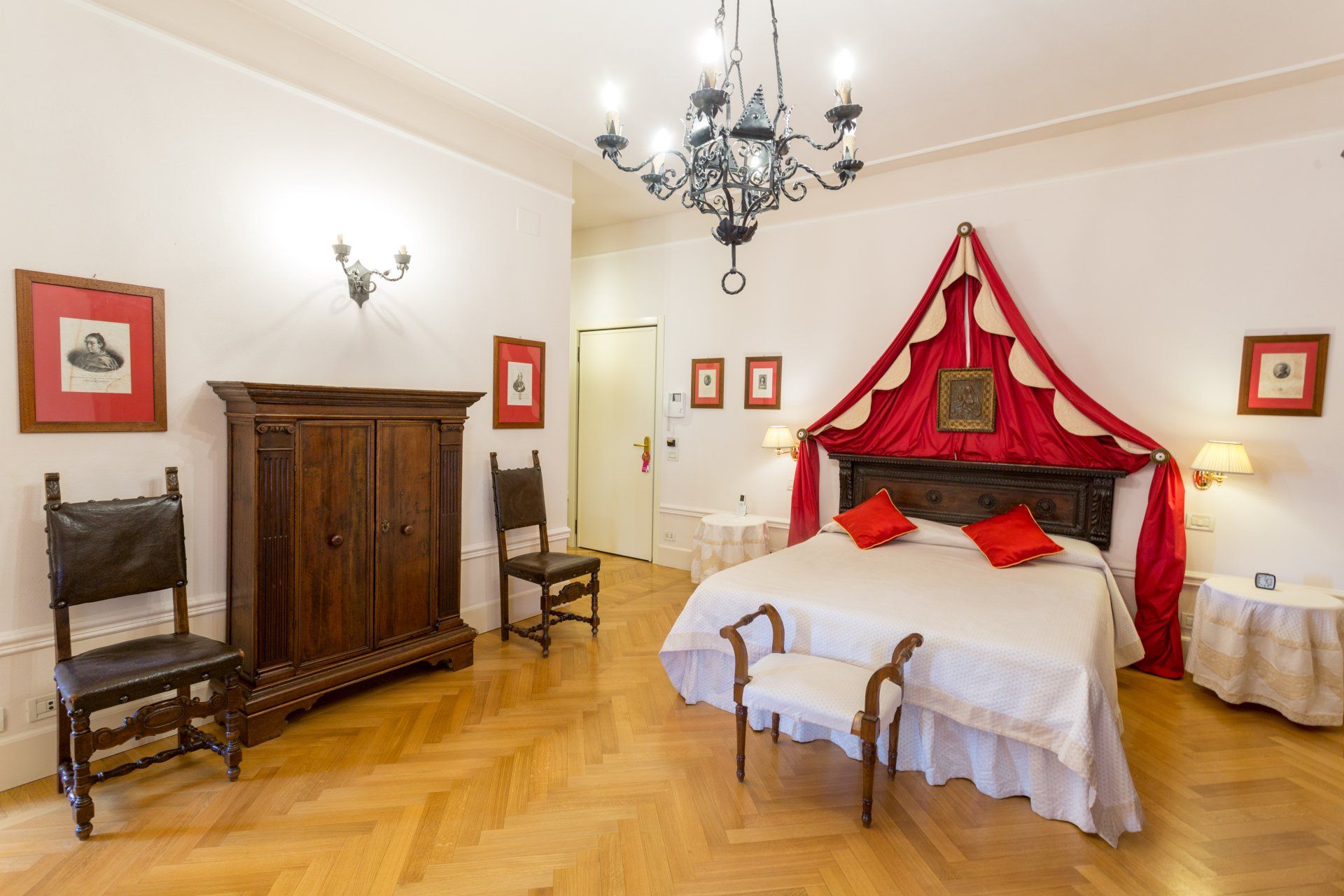 Camera da letto con mobili antichi, grande letto con baldacchino rosso, pavimenti in legno.