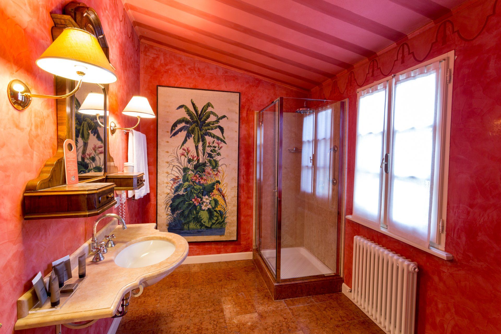 Bagno rosso con doccia, lavandino e dipinto di una palma.
