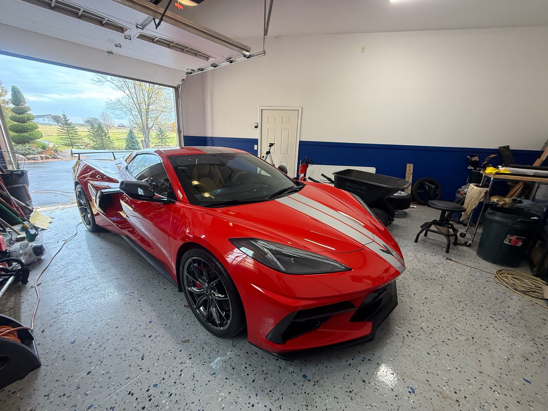 Red sports car in a garage with tools and equipment around it