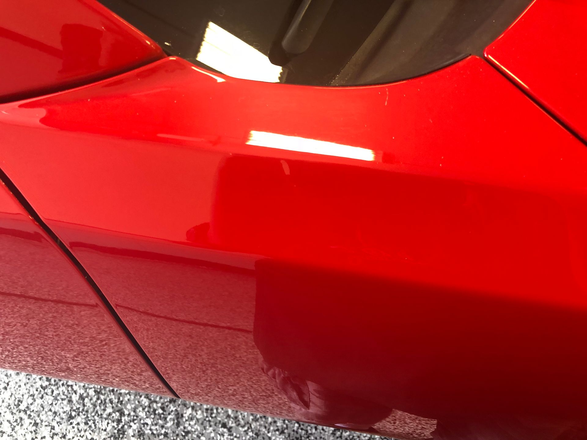 Close-up of a glossy red car door and side panel with reflections.