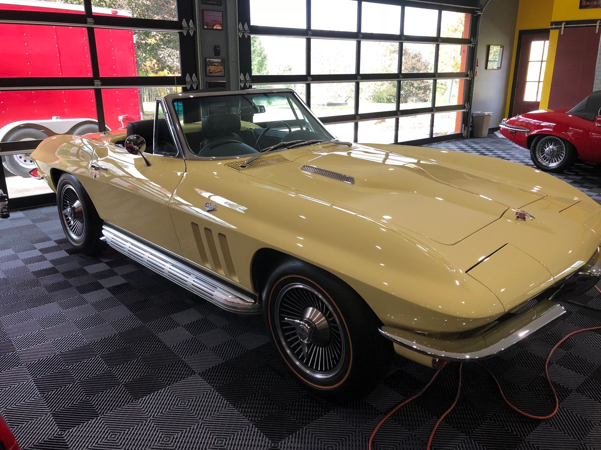 Vintage cream convertible sports car in a garage, with a red car in the background