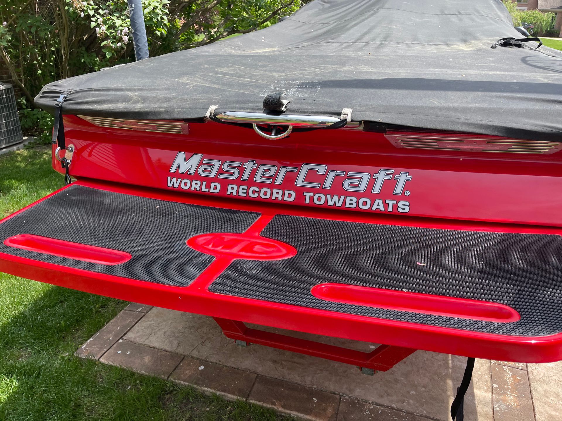 Red MasterCraft boat with “World Record Towboats” text, covered and parked outdoors on a trailer