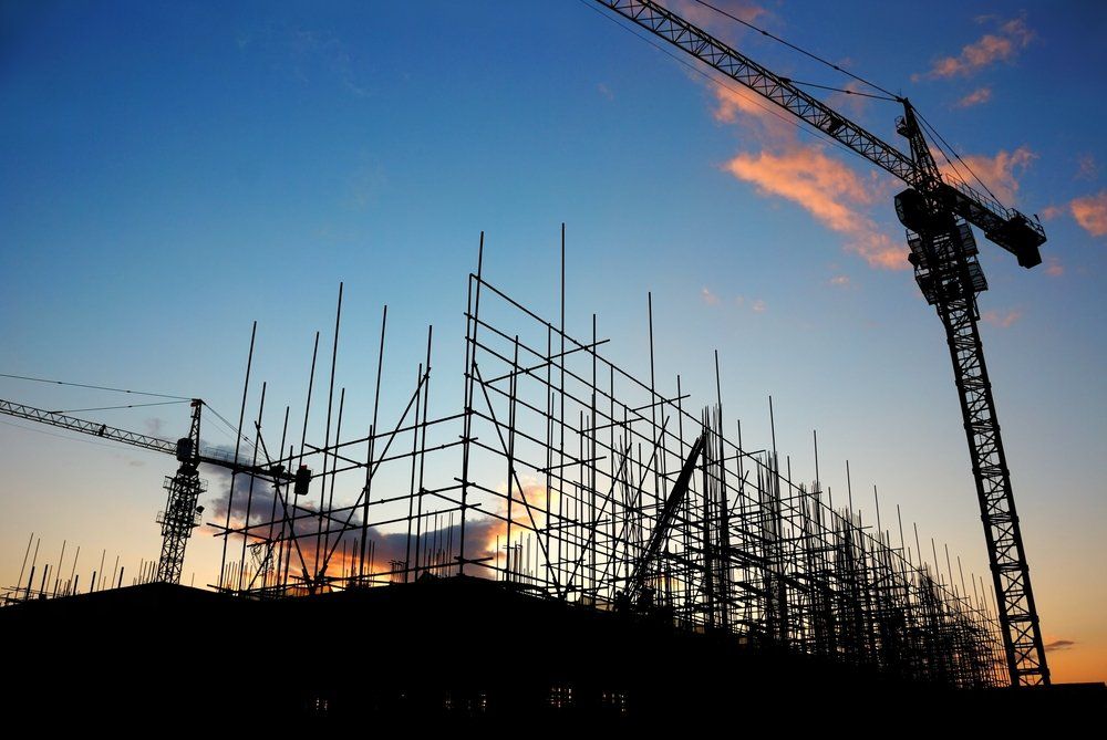 Un chantier de construction avec des grues et des échafaudages au coucher du soleil