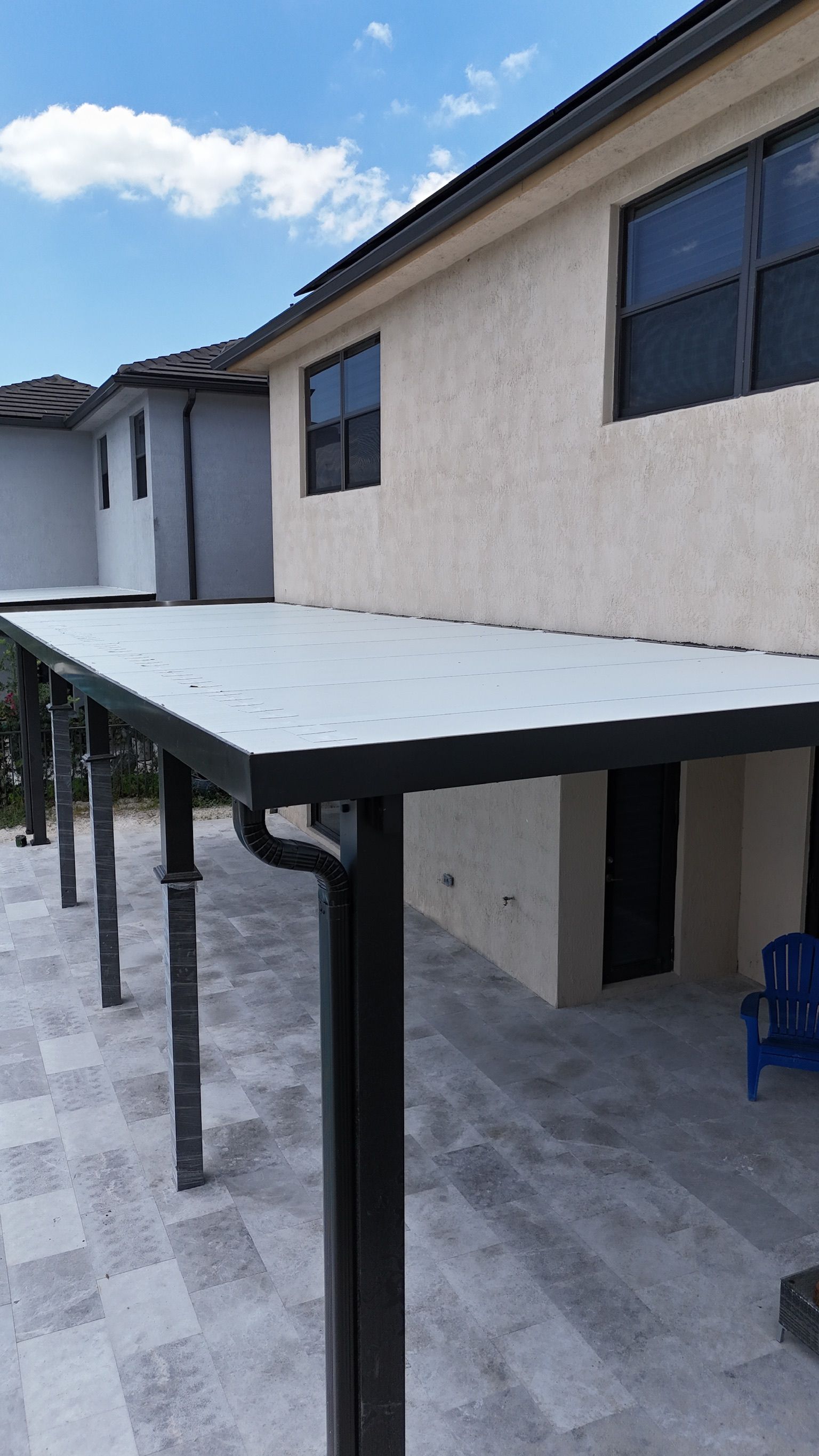 White patio canopy beside a beige building under a blue sky