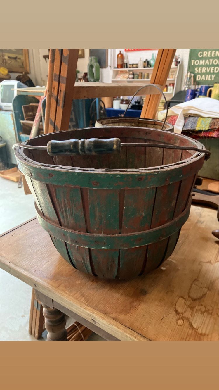 Old wooden bucket with green metal bands on a workbench in a workshop.