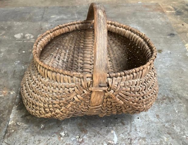 Woven wicker basket with a handle on a concrete floor