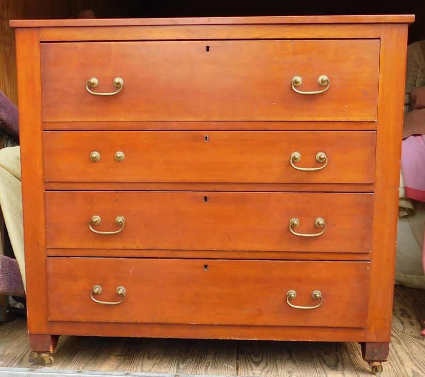Orange wooden dresser with four drawers and brass handles
