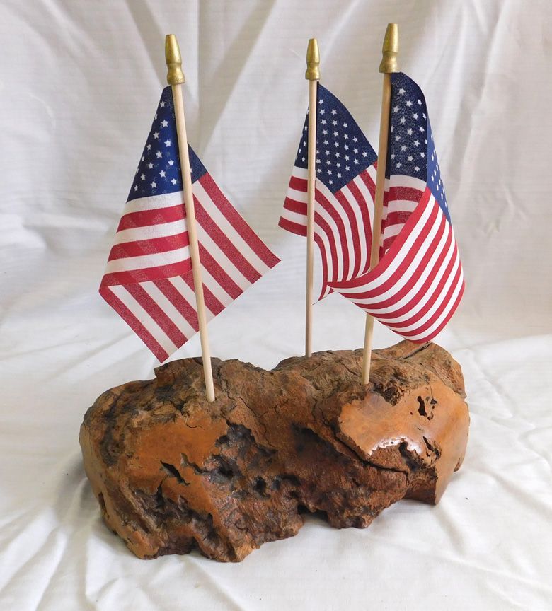 Three small U.S. flags on a rustic wood base against a white background