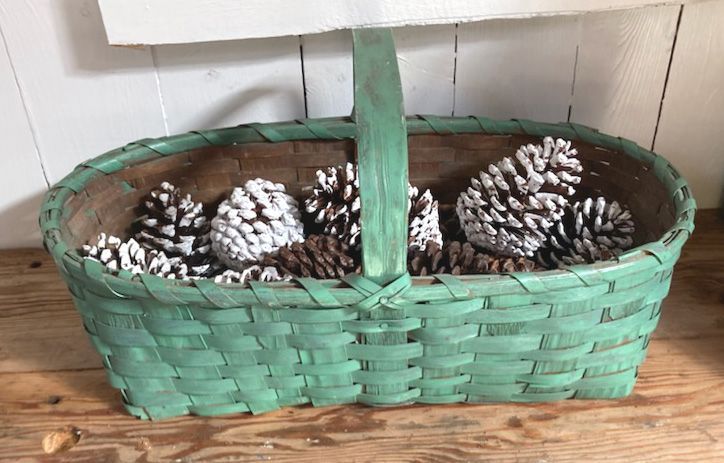 Green basket filled with pinecones on a wooden surface