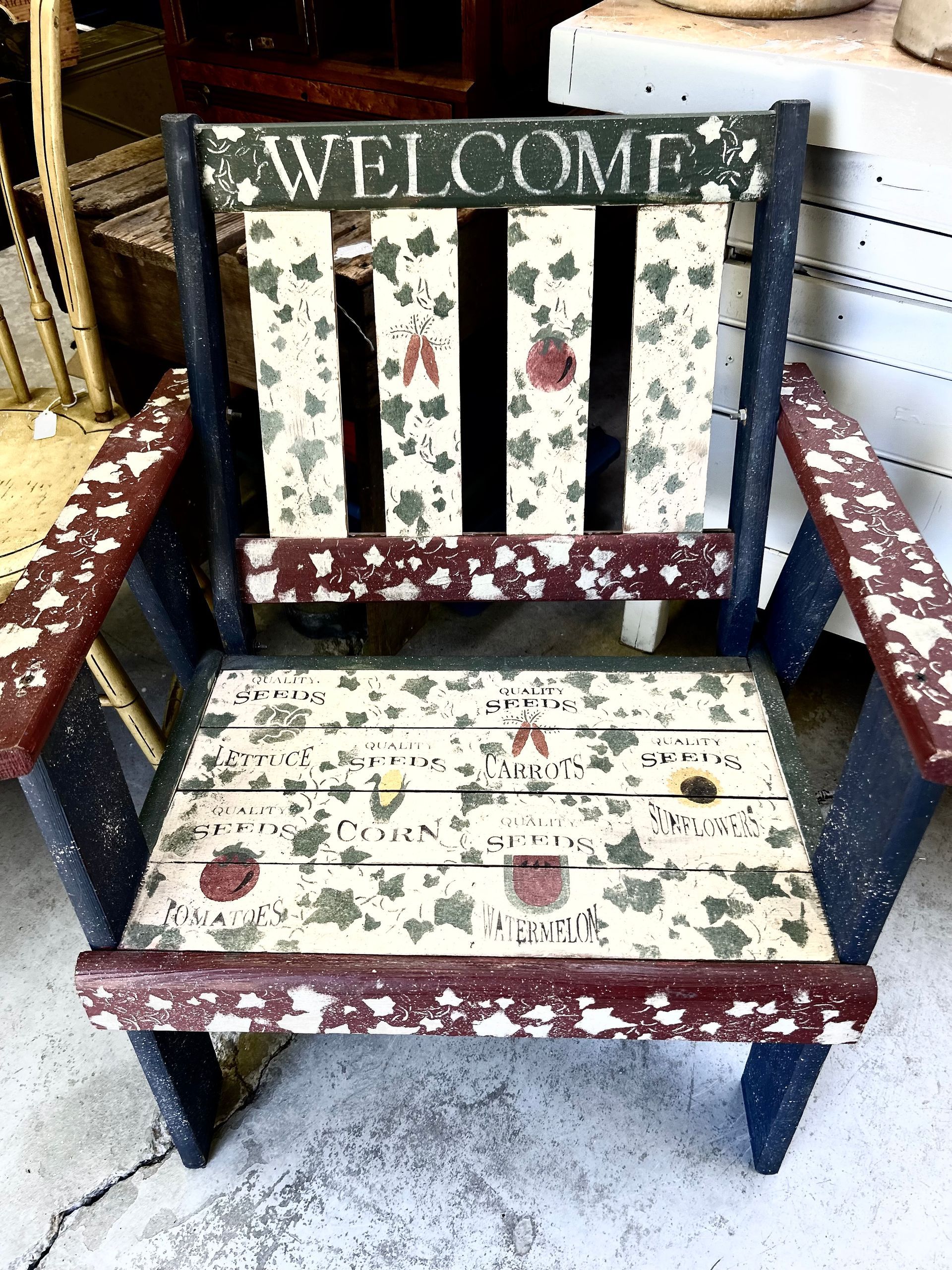 Floral-patterned wooden welcome chair with red and white upholstery and “WELCOME” sign on back