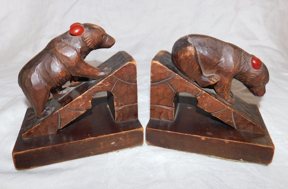 Two carved wooden monkeys on triangular bases, brown with red eyes, facing each other