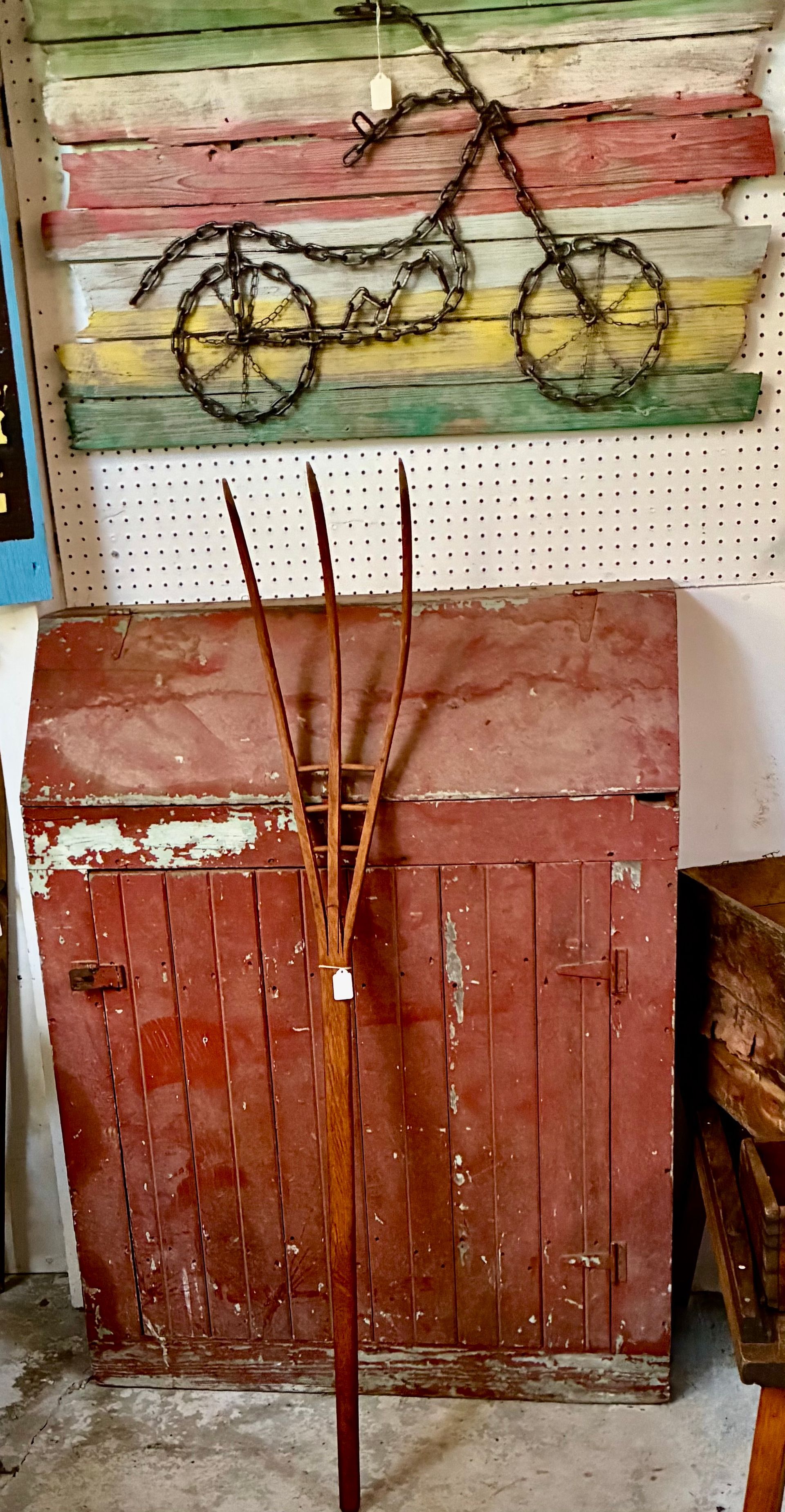 Rustic decor: weathered red cabinet with tall reeds beneath a painted bicycle wall hanging.