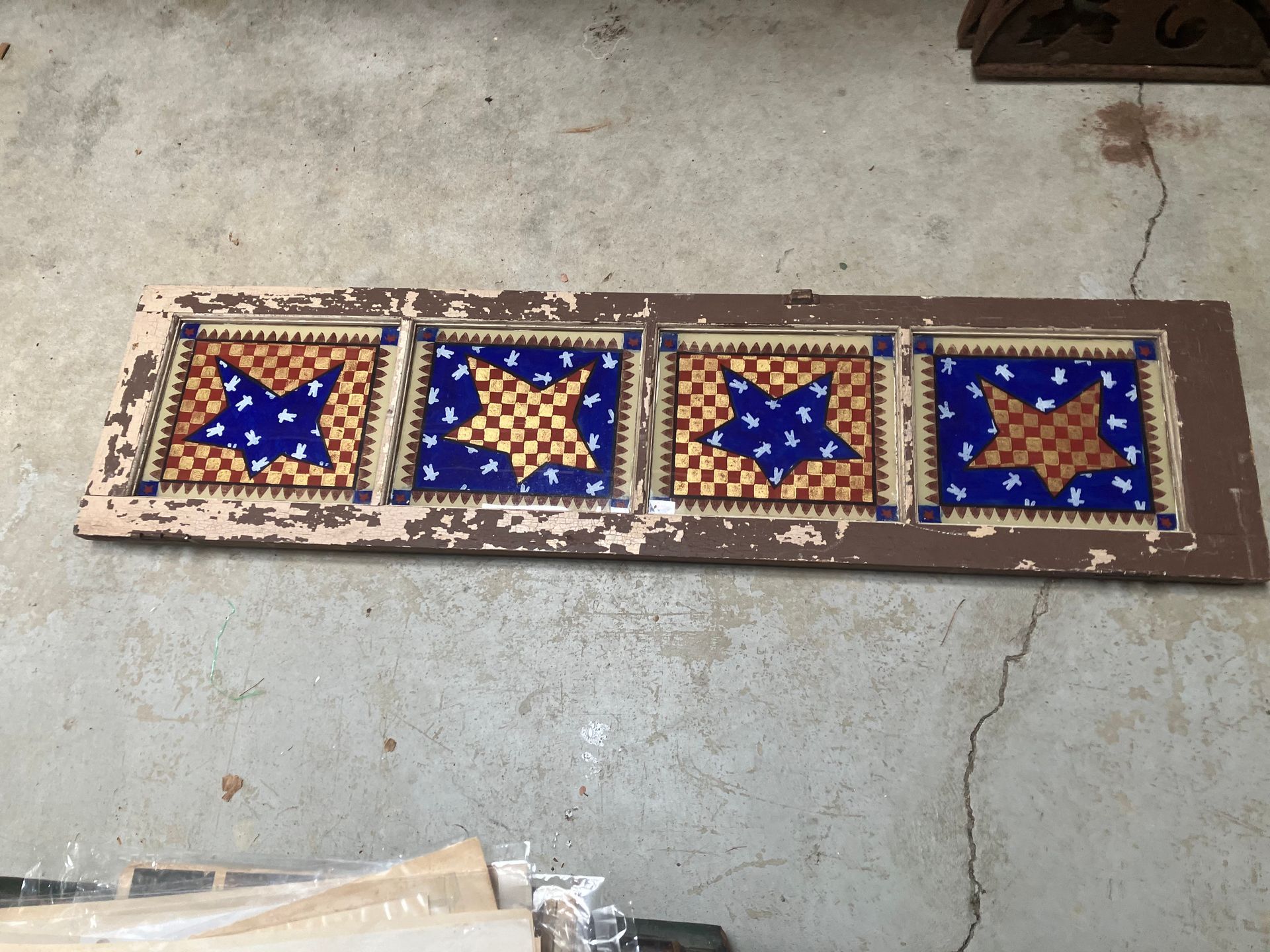 Four decorative star-pattern tile panels in blue, tan, and cream laid on a concrete floor.