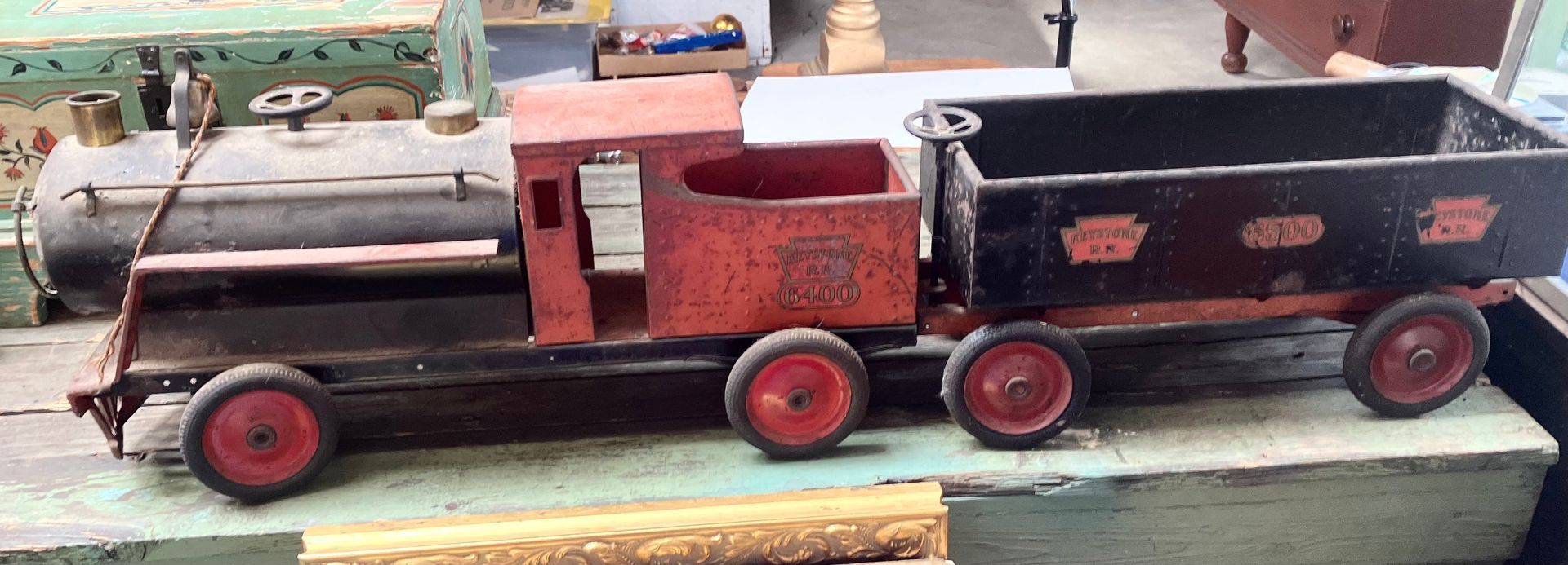 Black-and-red toy steam train on a table, with a locomotive and two passenger cars.