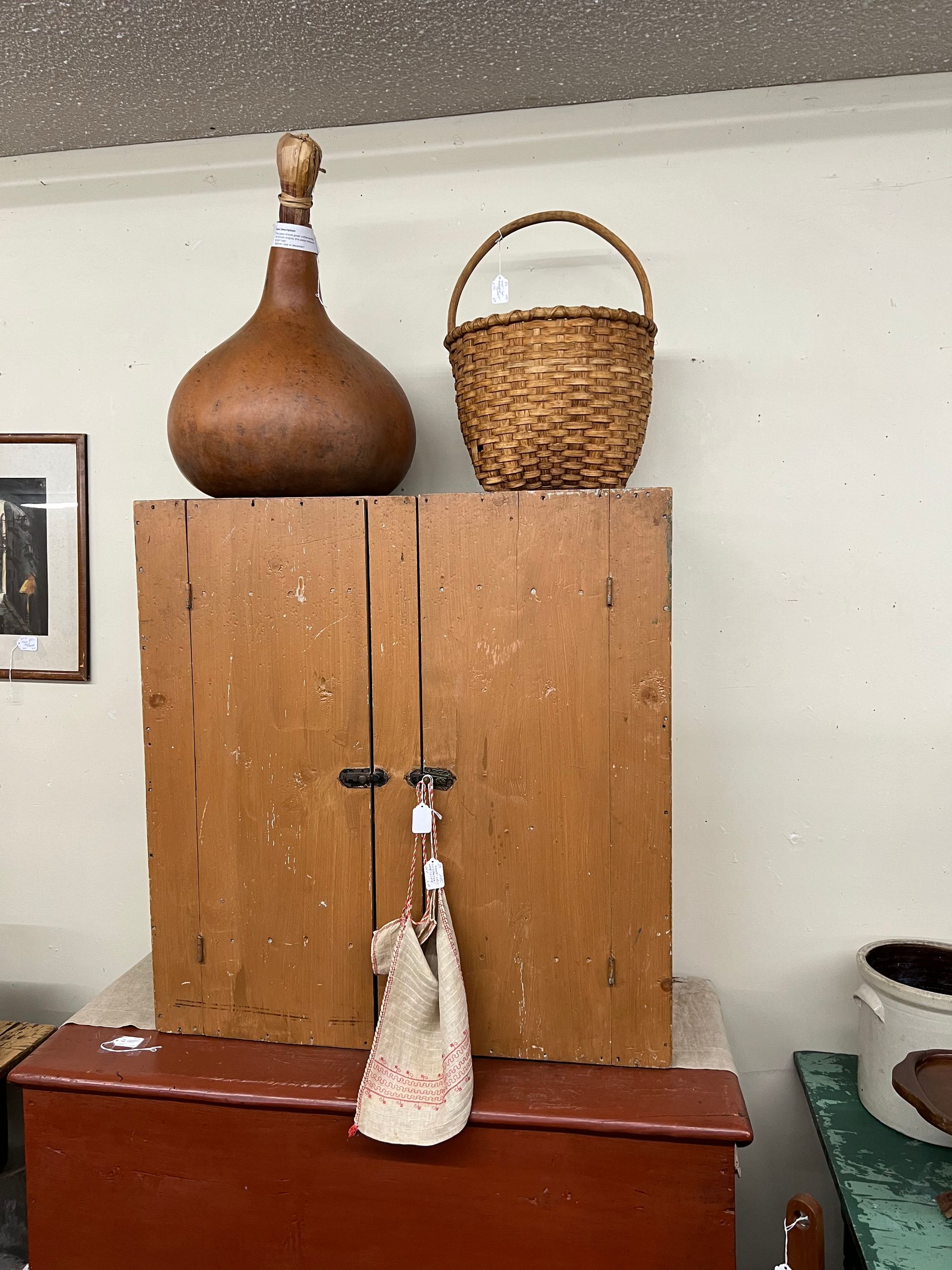 Wooden cabinet with a gourd, wicker basket, and hanging tassel in a room corner