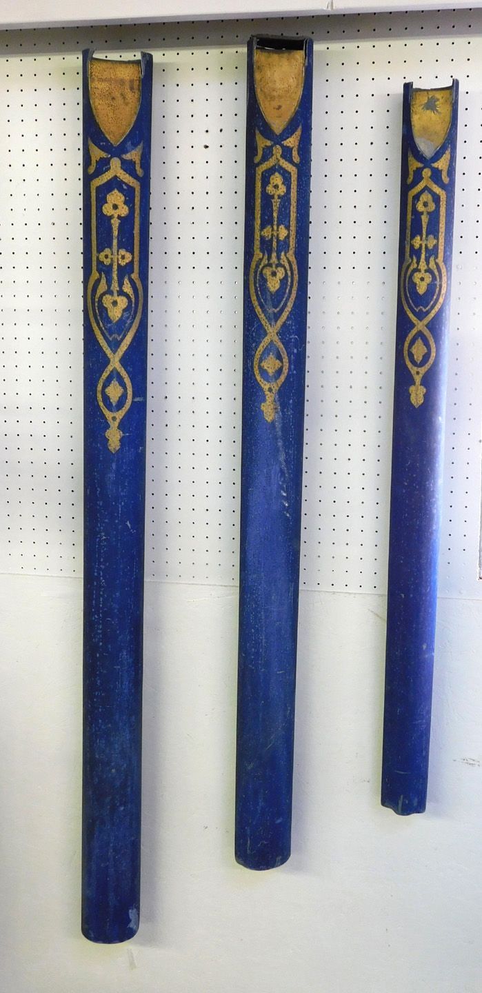 Three blue-and-gold decorative staffs hanging vertically on a pegboard wall.