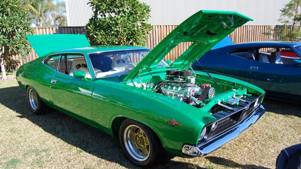 a green Ford classic car with an open hood
