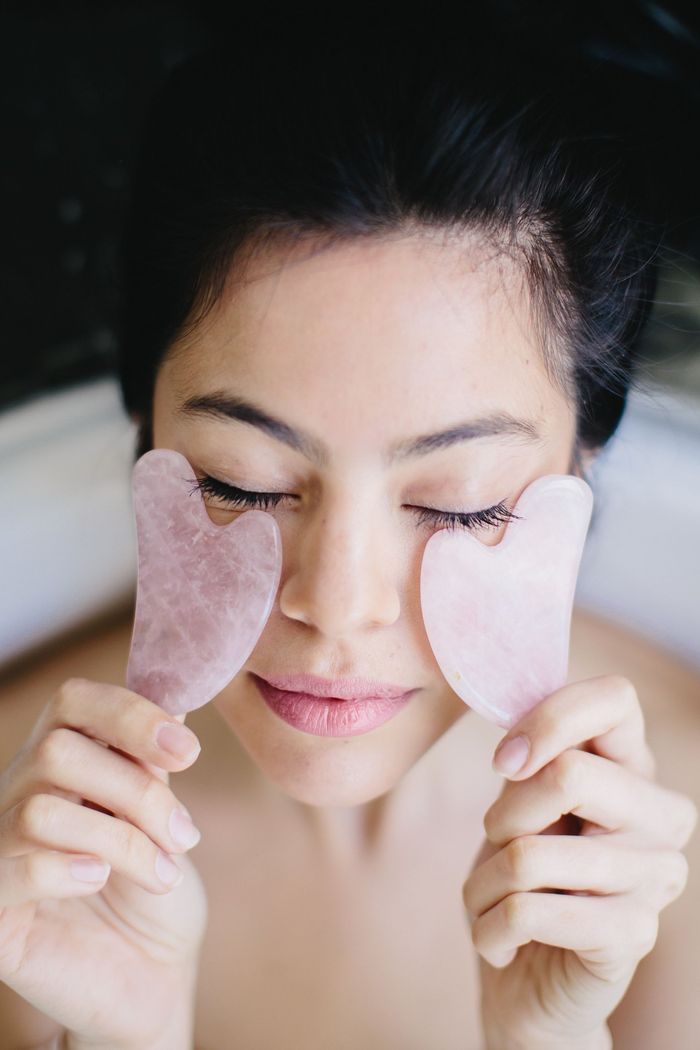 A woman is laying down while receiving a facial treatment.