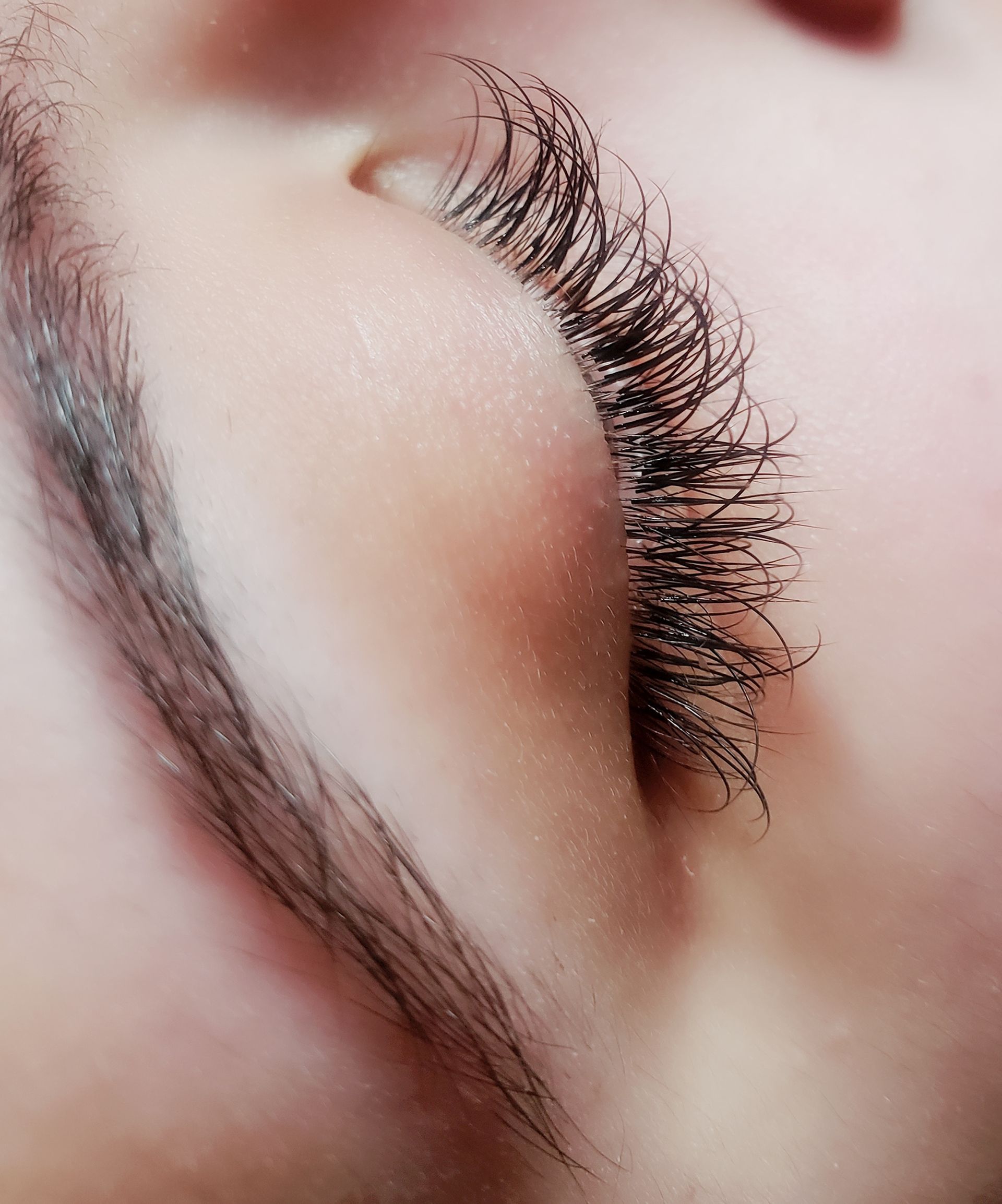 A close up of a woman's eye with long eyelashes at a salon.