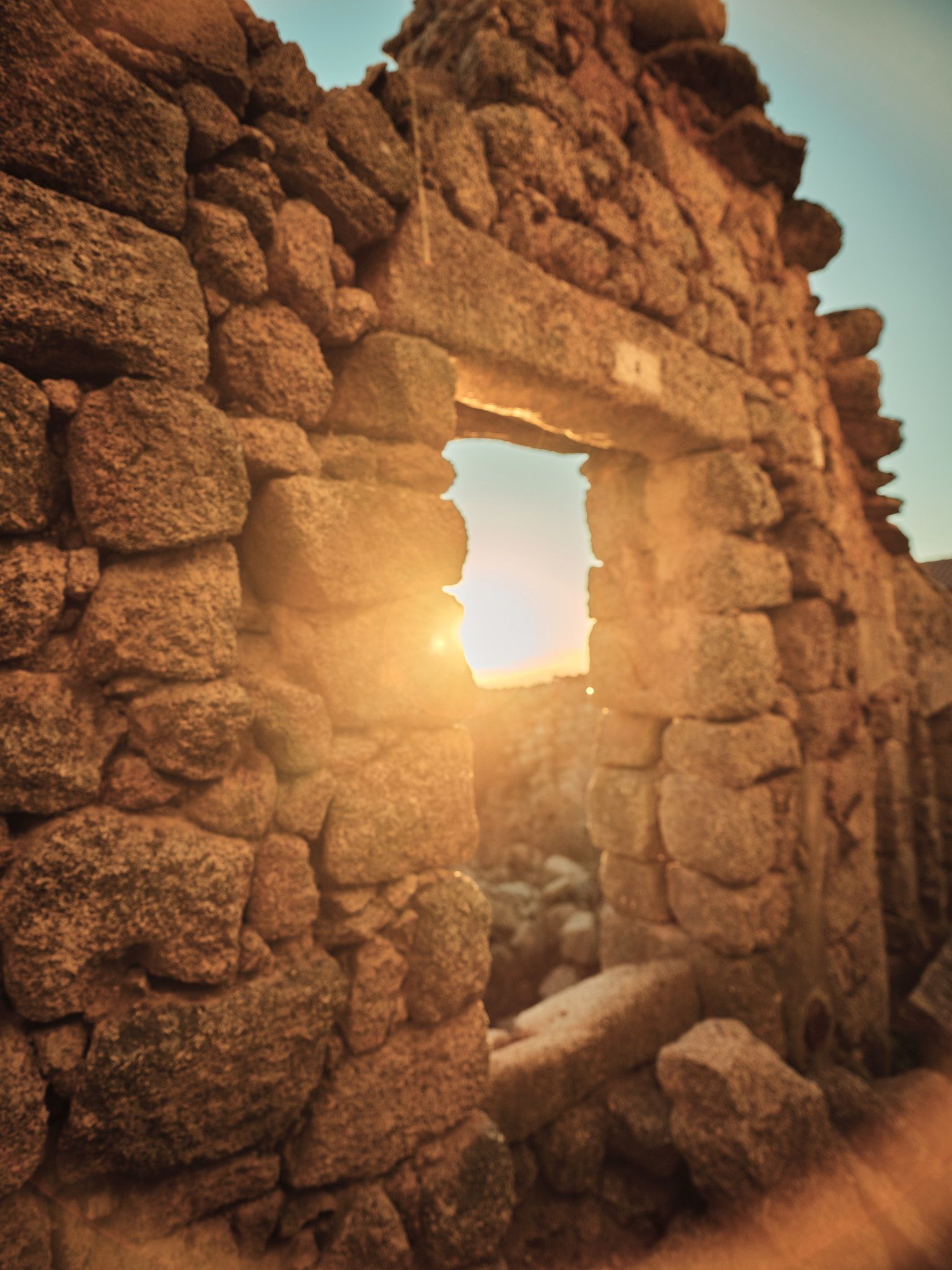 The sun is shining through the window of an old stone building.