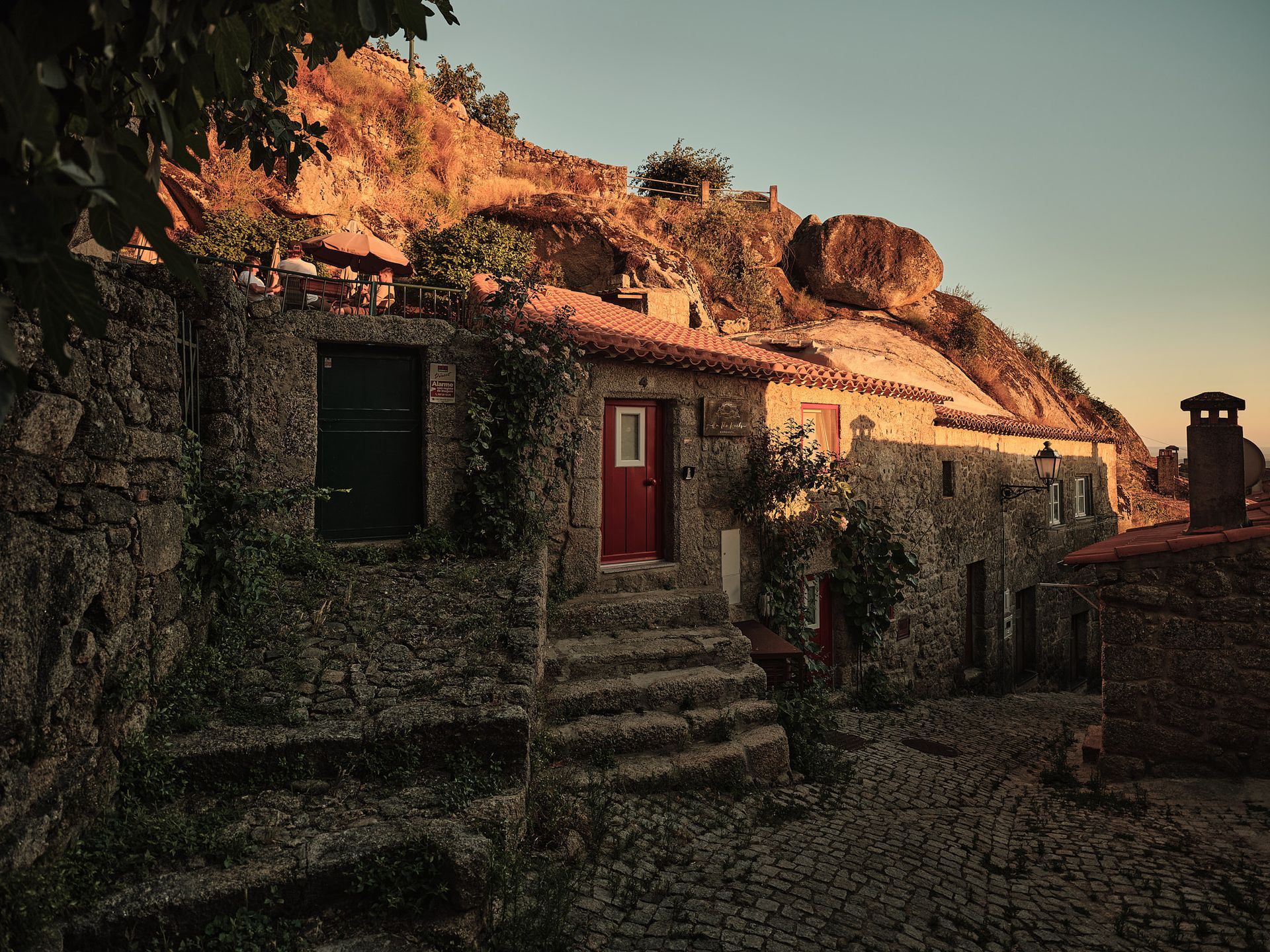 A stone building with a red door and stairs leading up to it.